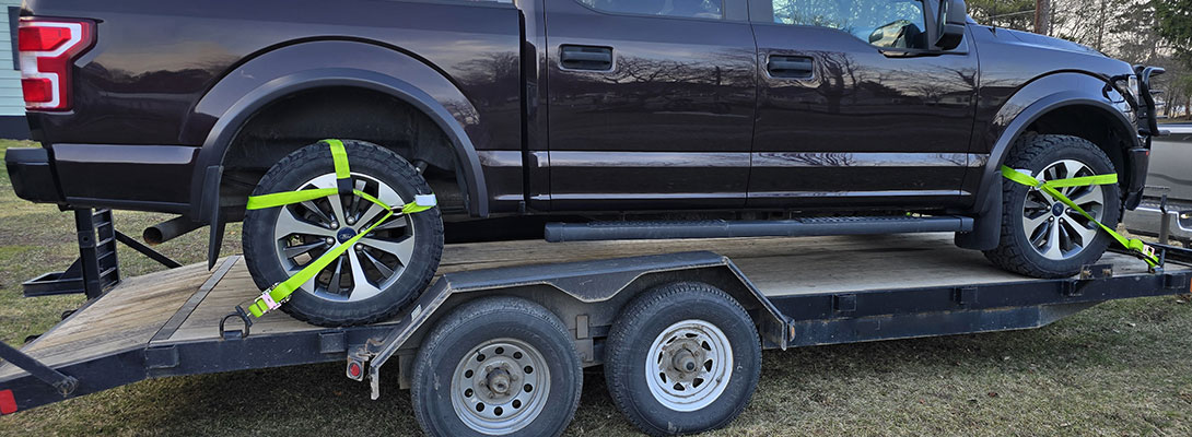 Side mount wheel straps securing truck tires on trailer